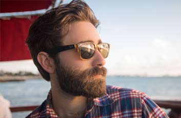 Chico luciendo un bonito pelo y barba y que lleva unas gafas de sol - Injerto Capilar Gijón